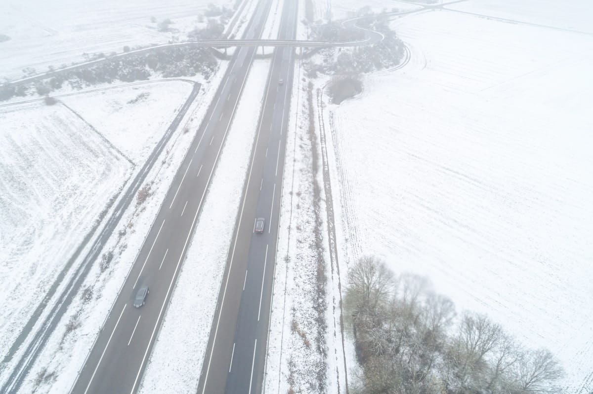 Snelweg A-52 in de provincie Ourense met rijbanen en omliggende velden bedekt met sneeuw.