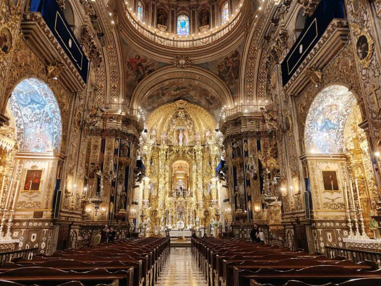 Het rijk versierde interieur van de Basilica de San Juan de Dios in Granada, met vergulde altaarstukken, marmeren details en een indrukwekkende koepel.