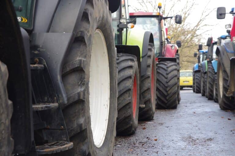 Rij landbouwtractoren opgesteld langs de weg tijdens een boerenprotest.
