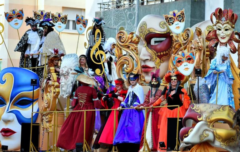 Carnavalsoptocht in Cádiz met deelnemers in historische kostuums en grote decoratieve maskers op een praalwagen
