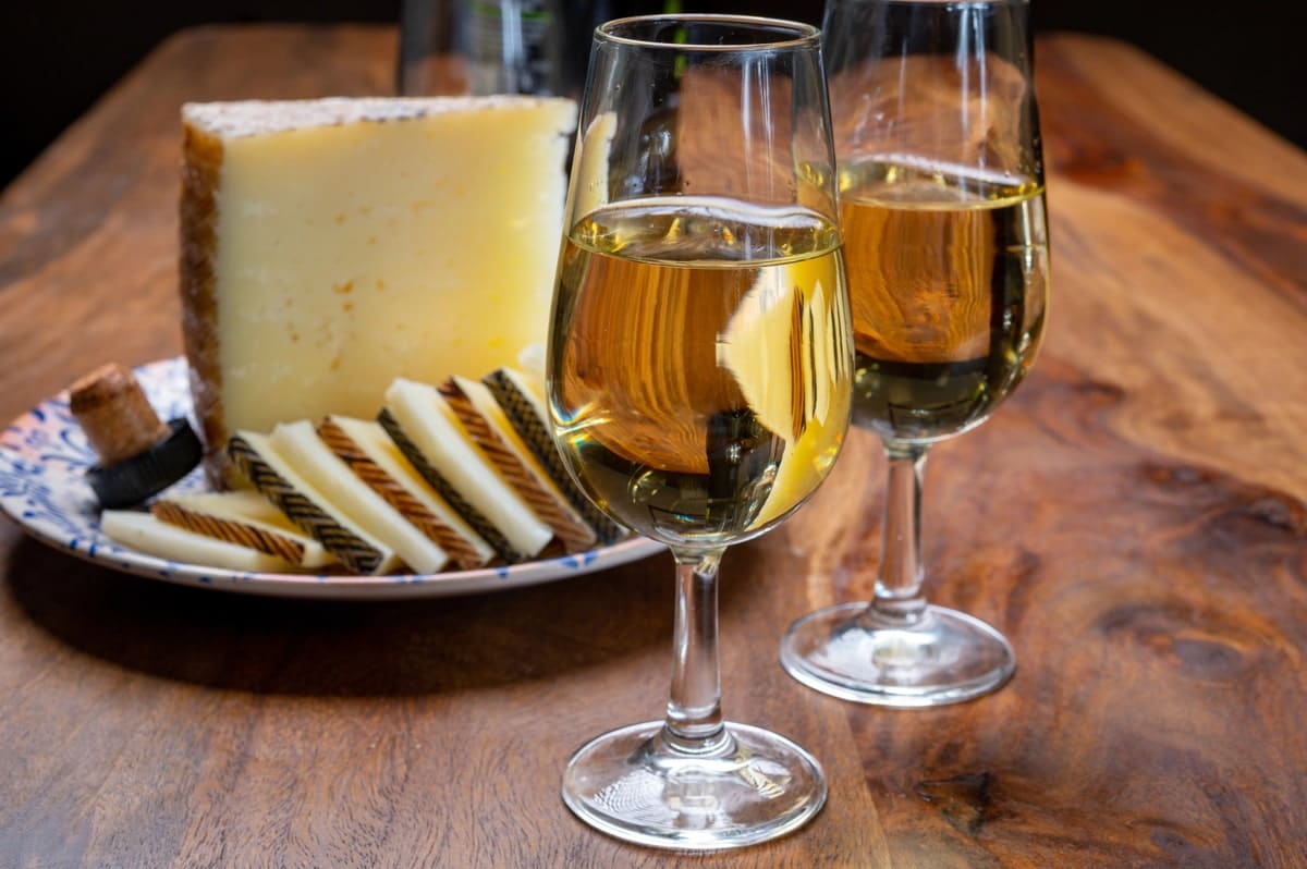 Twee glazen sherry naast een bordje met kaas, typisch voor de gastronomie van Jerez de la Frontera.