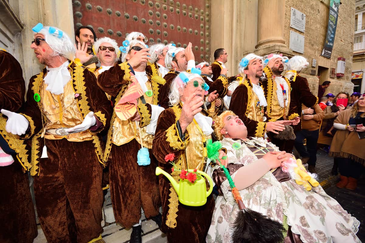 Groep verklede deelnemers in historische kostuums die zingend optreden tijdens het carnaval in Cádiz