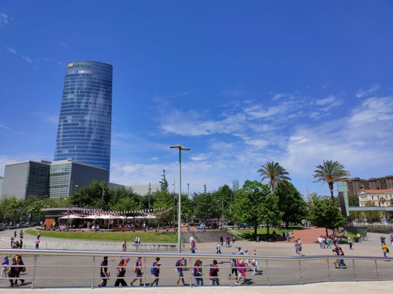 Glazen kantoortoren van Iberdrola in Bilbao met park en voetgangers op de voorgrond