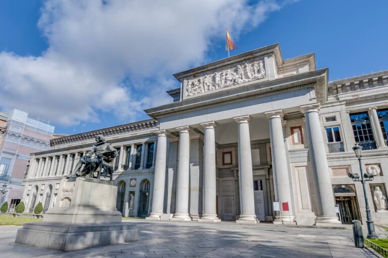 Gevel van het Museo Nacional del Prado in Madrid met zuilen en het standbeeld van Diego Velázquez op de voorgrond.