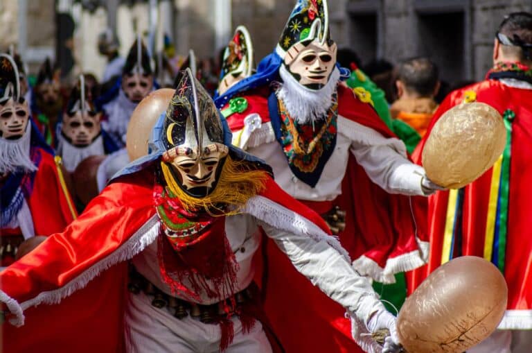 Pantallas met traditionele maskers en rode capes tijdens het carnaval in Xinzo de Limia.
