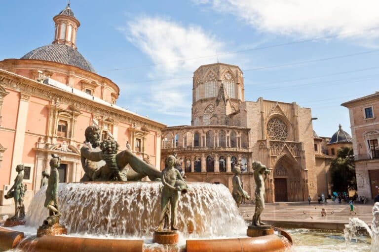 Fontein met bronzen beelden op Plaza de la Virgen met de kathedraal van Valencia op de achtergrond.