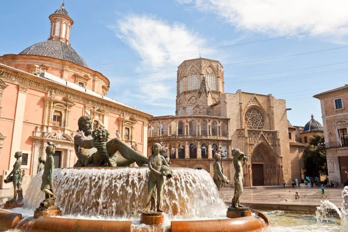 Fontein met bronzen beelden op Plaza de la Virgen met de kathedraal van Valencia op de achtergrond.