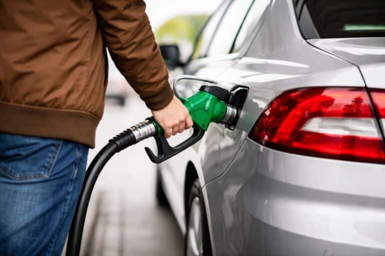 Persoon tankt auto bij benzinepomp bij een tankstation