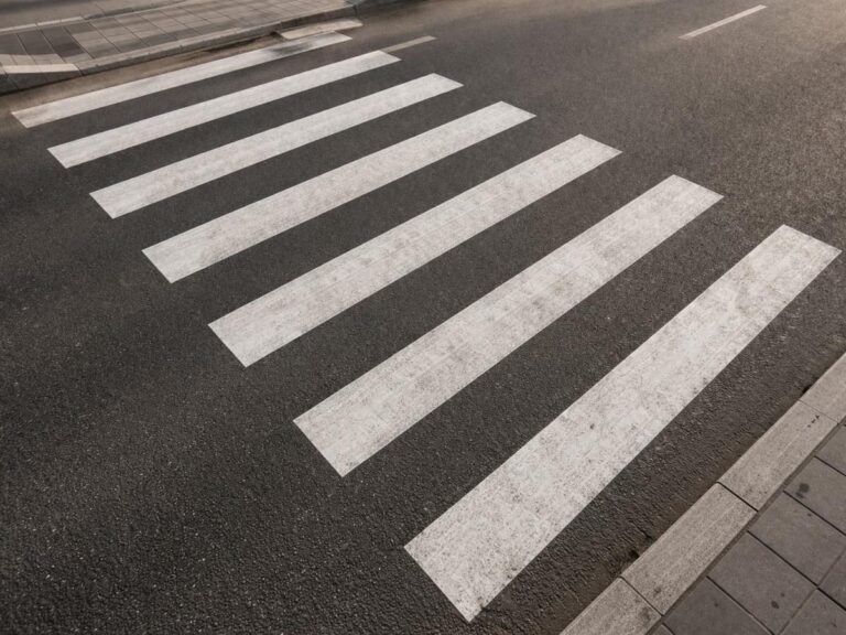 Zebrapad schuin van boven gezien op een asfaltstraat met trottoirrand zichtbaar