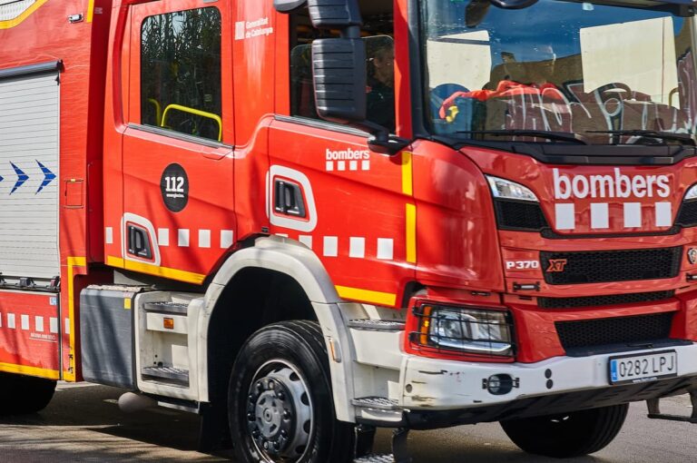 Rode brandweerwagen met opschrift ‘bombers’ en noodnummer 112, geparkeerd op straat