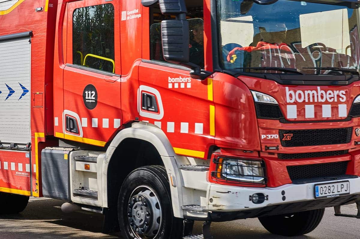 Rode brandweerwagen met opschrift ‘bombers’ en noodnummer 112, geparkeerd op straat