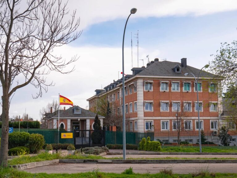Bakstenen gebouw van het Palacio de la Moncloa in Madrid met Spaanse vlag en bomen op de voorgrond