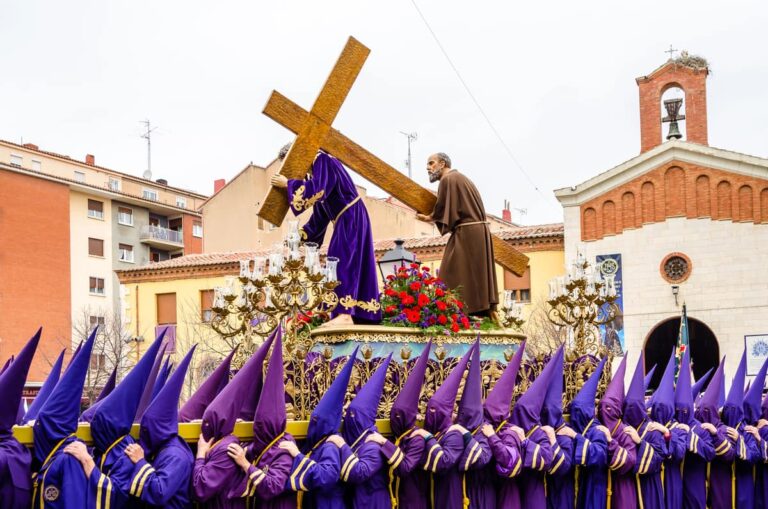 Paasprocessie (Semana Santa) in Palencia met dragers in paarse gewaden die een religieus beeld van Jezus met kruis door de straat dragen