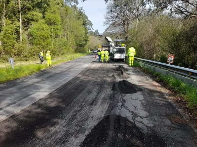 Wegwerkers herstellen beschadigd asfalt op een landelijke weg in Asturias na stormschade