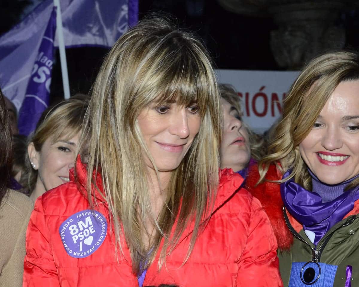 Begoña Gómez in een rode jas tijdens een demonstratie op Internationale Vrouwendag in Madrid, omringd door andere deelnemers.