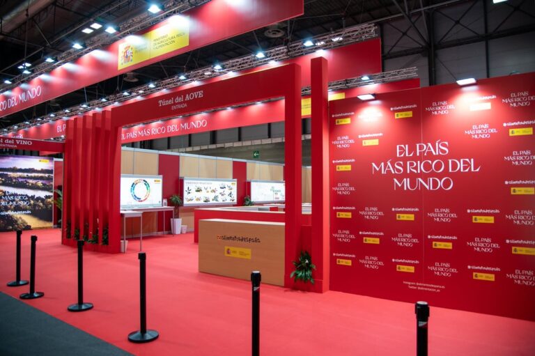 Stand van het Spaanse ministerie van Landbouw op de Salón Gourmets in Madrid, met rode beursopstelling en de slogan ‘Het rijkste land ter wereld’ in het Spaans.