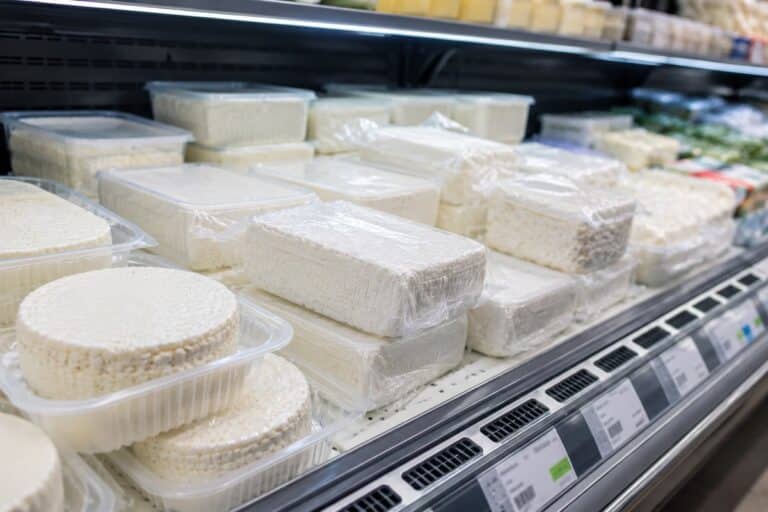 Verpakte verse koekaas in een gekoelde supermarktvitrine zonder herkenbare merken of verpakkingen.