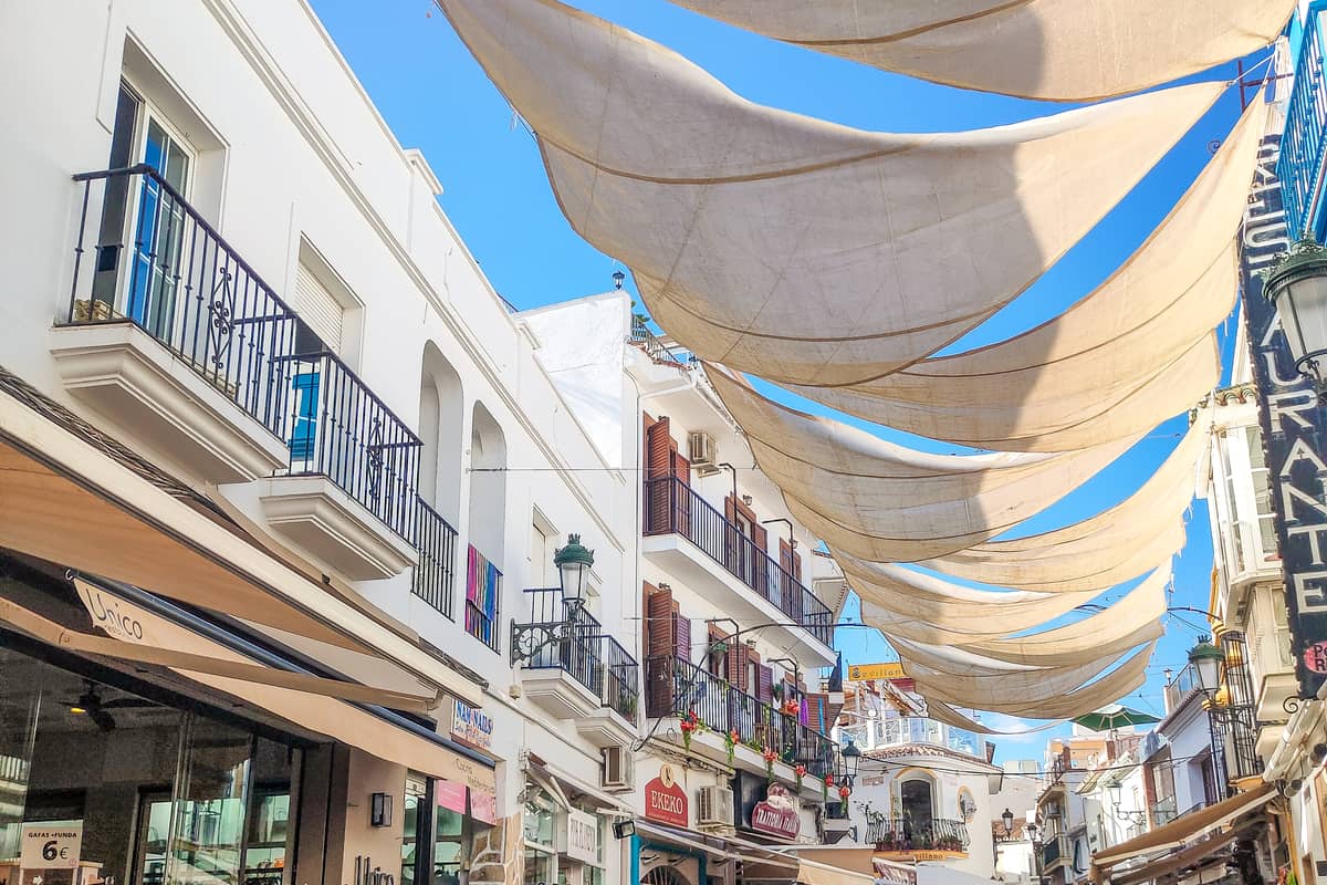 Schaduwdoeken hangen boven een straat in Spanje tijdens zonnig weer.