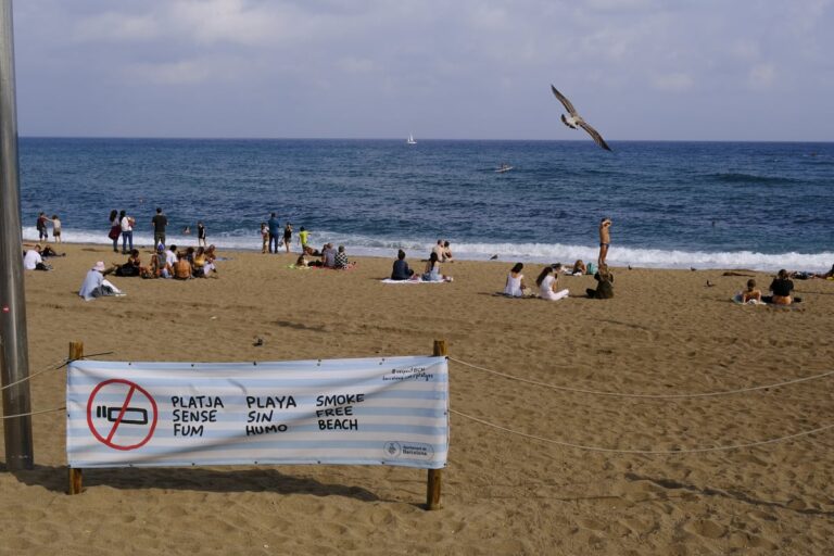 Bord voor een rookvrij strand op een strand in Barcelona met bezoekers op de achtergrond.